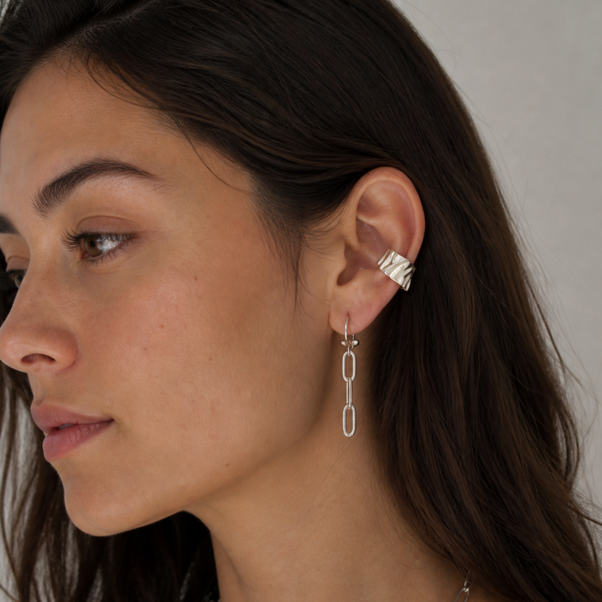 Woman wearing silver hoop earrings with a neutral background
