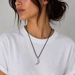 Woman wearing a white t-shirt and a necklace with a pendant against a neutral background