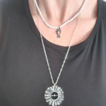 Silver necklace with a sunflower pendant on a black shirt