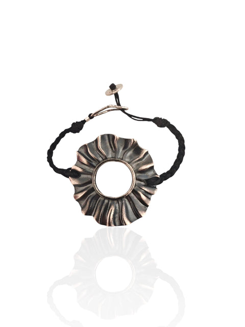 Helios oxidized silver sun bracelet (4×4 cm) on braided black cord, worn on wrist , Athenart Jewelry, handmade in Athens.”