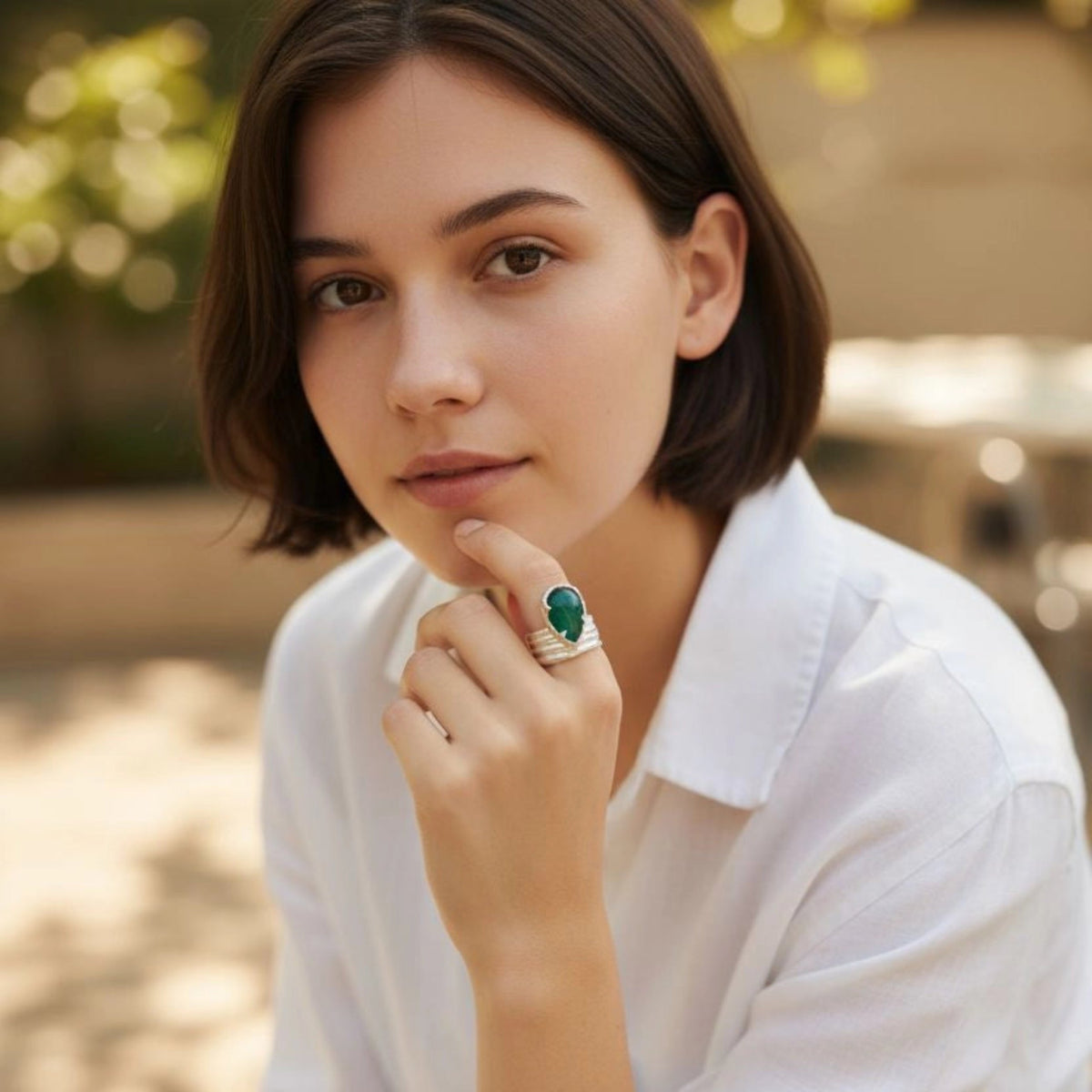 Woman wearing a white shirt and beige pants with a blurred outdoor background