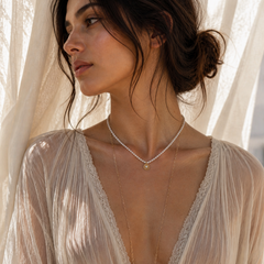 Woman wearing pearl necklace with sun  charm, wholesale jewelry, greek designers 