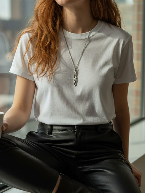 Athenais Drapé Pendant in silver on medium-length chain, lifestyle portrait indoors with natural light