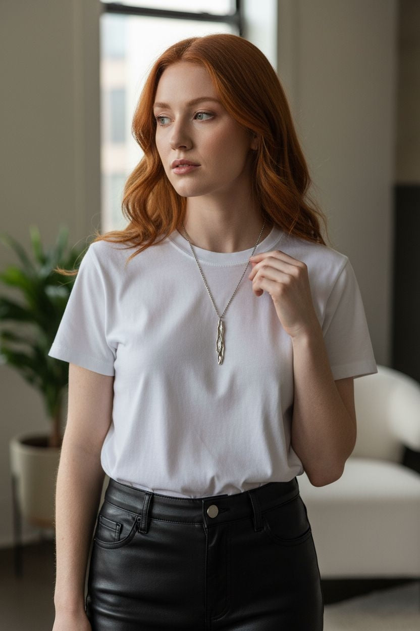 Model wearing Athenais Drapé Pendant in polished silver on long chain over white T-shirt, soft daylight