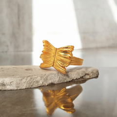 Gold butterfly-shaped object on a stone surface with a blurred background