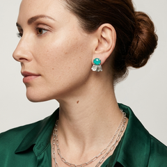 Woman wearing a green shirt with Chrysocolla earrings and silver necklaces on a neutral background