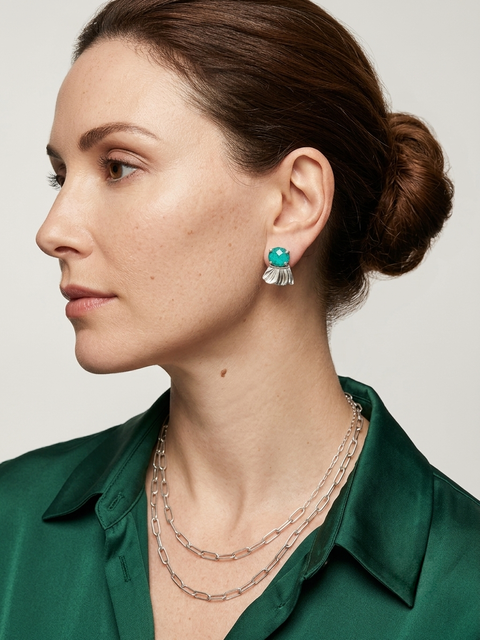 Woman wearing a green shirt with Chrysocolla earrings and silver necklaces on a neutral background