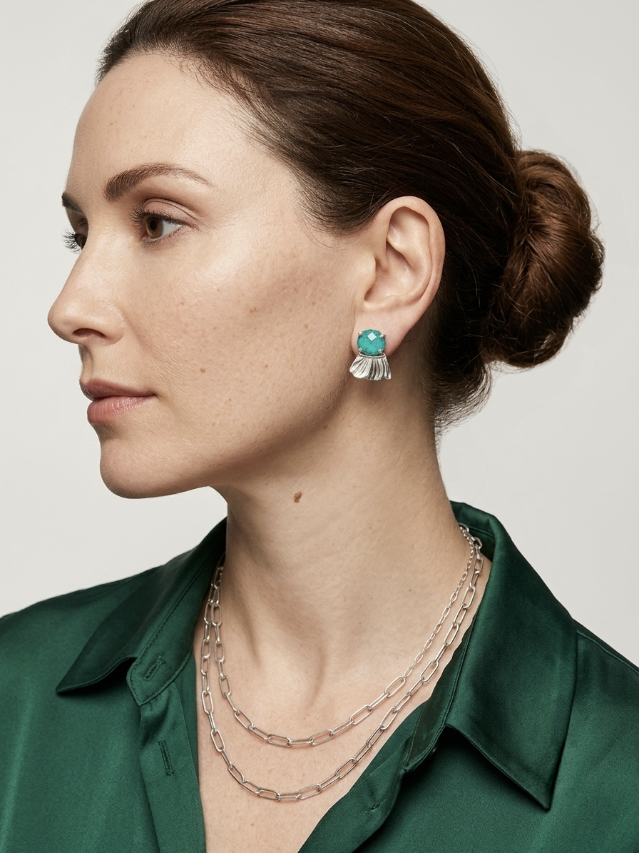 Woman wearing a green shirt with Chrysocolla earrings and silver necklaces on a neutral background