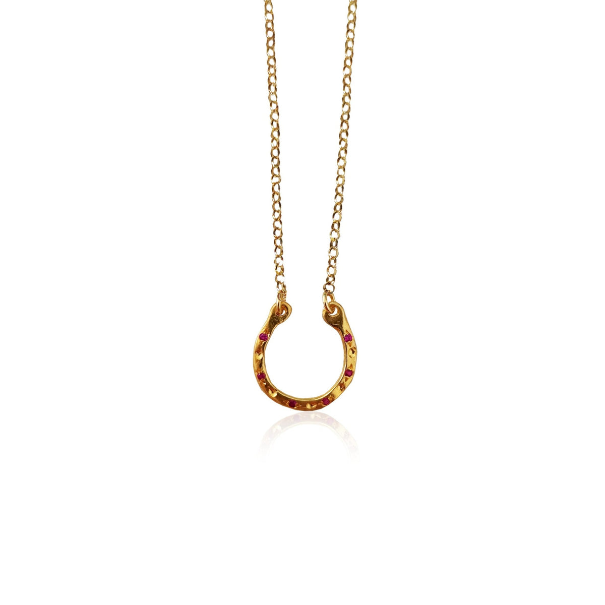 Gold horseshoe pendant necklace by Athenart, featuring red zircons and a delicate gold chain, inspired by traditional good luck symbols.