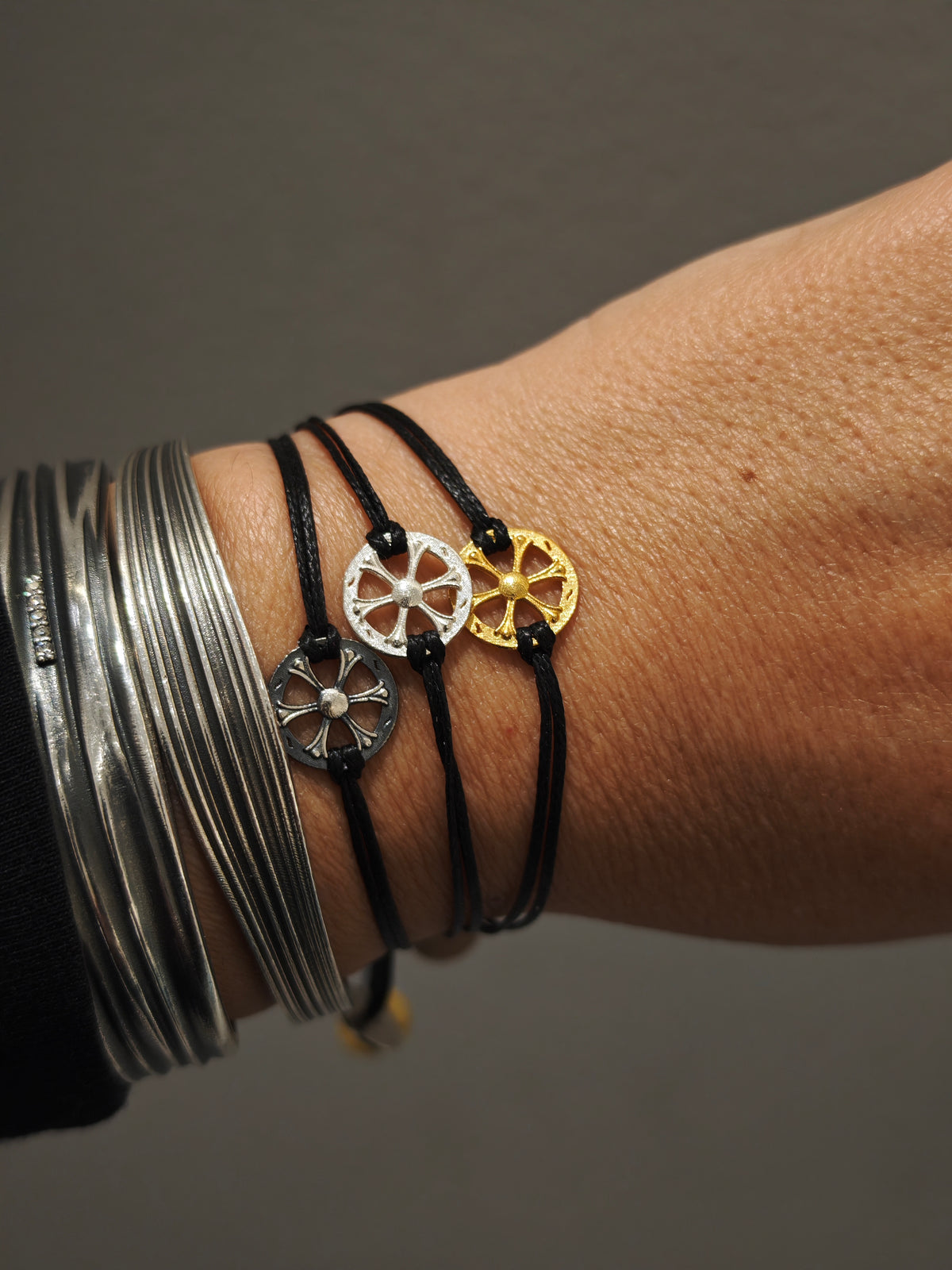Three Wheel of Fortune silver cord bracelets in silver, oxidized and gold-plated finishes, styled with sculptural silver cuffs.