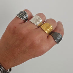 Hand wearing multiple rings on a plain background