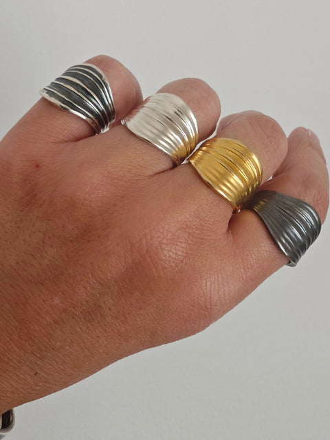 Hand wearing multiple rings on a plain background