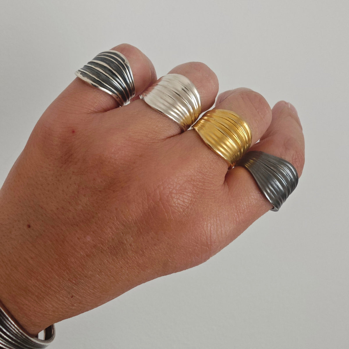 Hand wearing multiple rings on a plain background