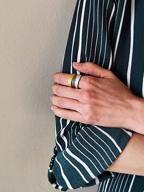 Person wearing a dark green and white striped shirt against a beige wall.