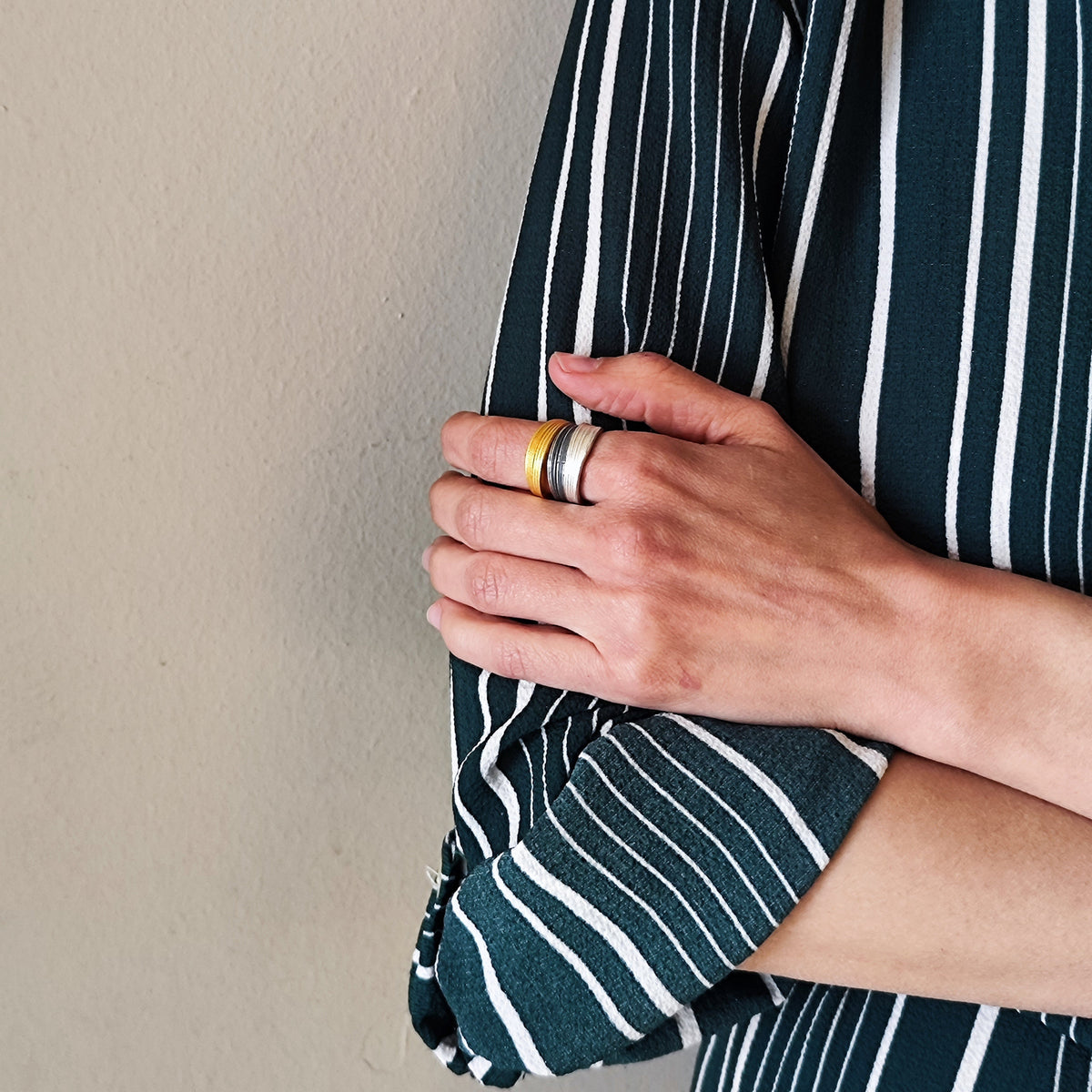 Person wearing a dark green and white striped shirt against a beige wall.