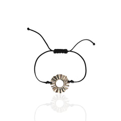 Black cord bracelet with a silver circular charm on a white background