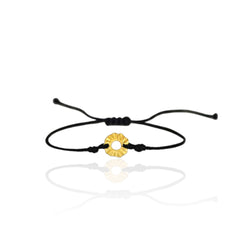 Black cord bracelet with a gold circular charm on a white background