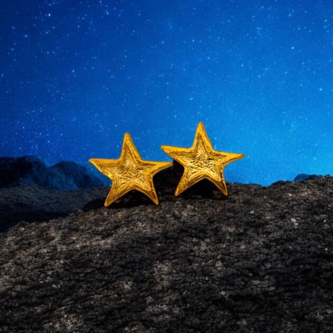 Gold-plated Asteria star earrings on stone with night sky background