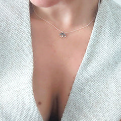 Necklace with a small pendant worn by a person against a light background