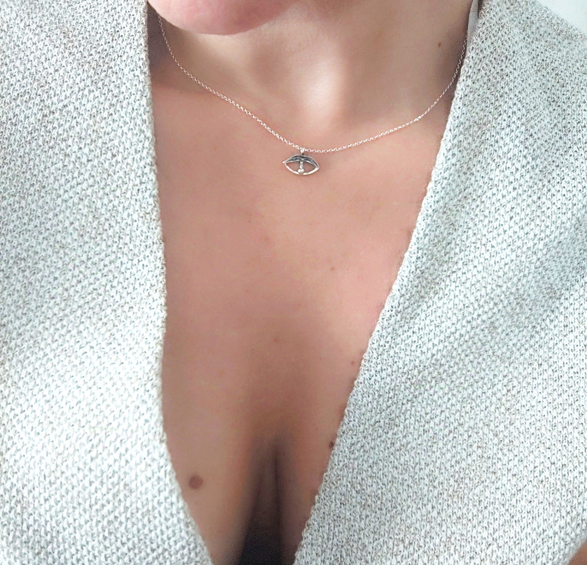 Necklace with a small pendant worn by a person against a light background