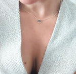 Necklace with a small pendant worn by a person against a light background